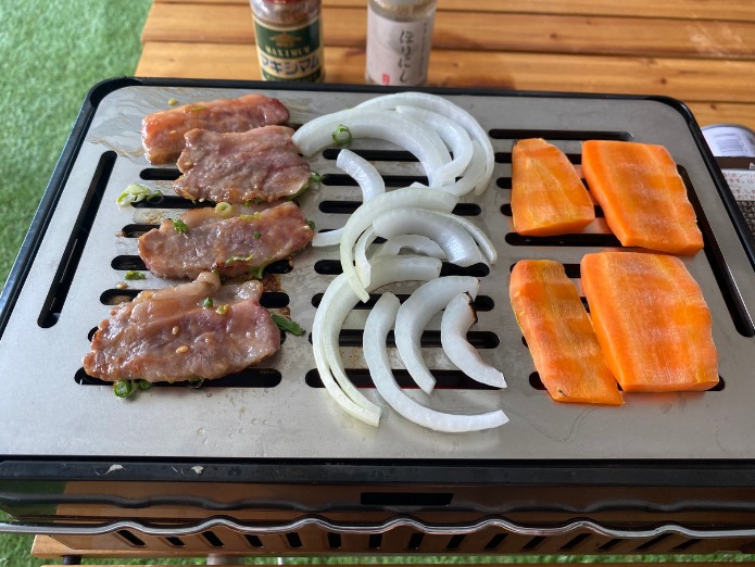 鉄板に肉や野菜を置いている画像