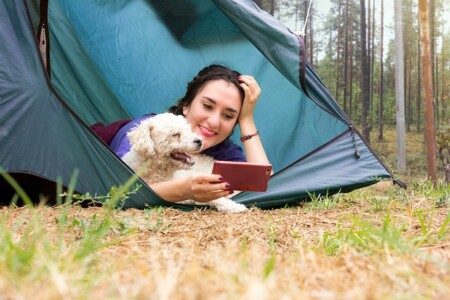 キャンプをしている女性と犬のイメージ