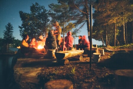 夜間の木の近くの焚き火の近くにいる人々のグループ